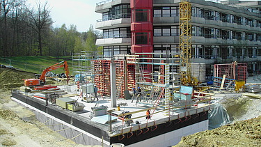 Foto während der Bauzeit mit Bagger und fertigem Unteregschoss