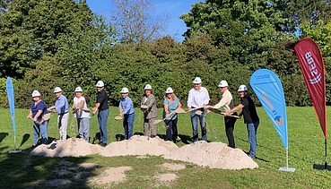 Foto von Menschen, die mit einem Spatenstich Sand von einem Hügel werffen