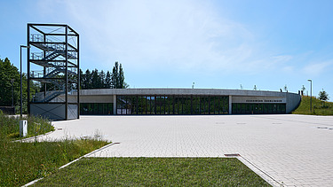 Foto Frontalansicht Gebäude mit Übungsplatz und Übungsturm