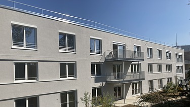 Foto von Längsseite des Gebäude mit Balkonen und Wiese