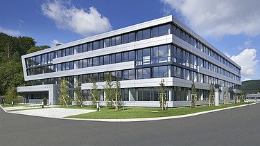 Foto Gebäudeecke mit Außenanlagen bei Sonnenschein