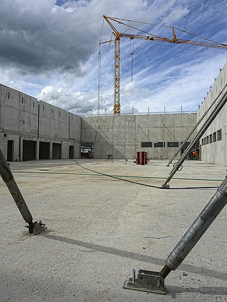 Foto von einem Innenhof als Baustelle mit Sichtbetonwänden, Sprießen und Kran