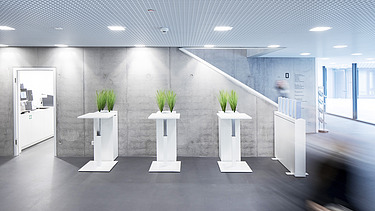 Foto Eingangsbereich mit Steh- und Wartetischen und Sichtbetonwand