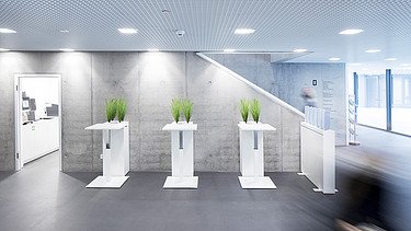 Foto Eingangsbereich mit Steh- und Wartetischen und Sichtbetonwand