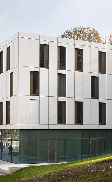 Foto von Gebäude mit weißer Fassade und Glaselementen im Erdgeschoss