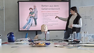 Eine Frau erklärt anhand eines Schaubild Rettung aus dem Gefahrenbereich
