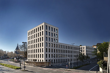 Foto von Gebäude von weiter weg mit Straße und blauem Himmel