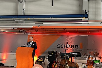 1 Mann steht auf einer Bühne und hält eine Rede
