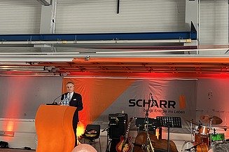 1 Mann steht auf einer Bühne und hält eine Rede
