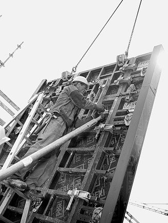 Foto in schwarz-weiß von einem Mann, der eine Wandschalung bearbeitet